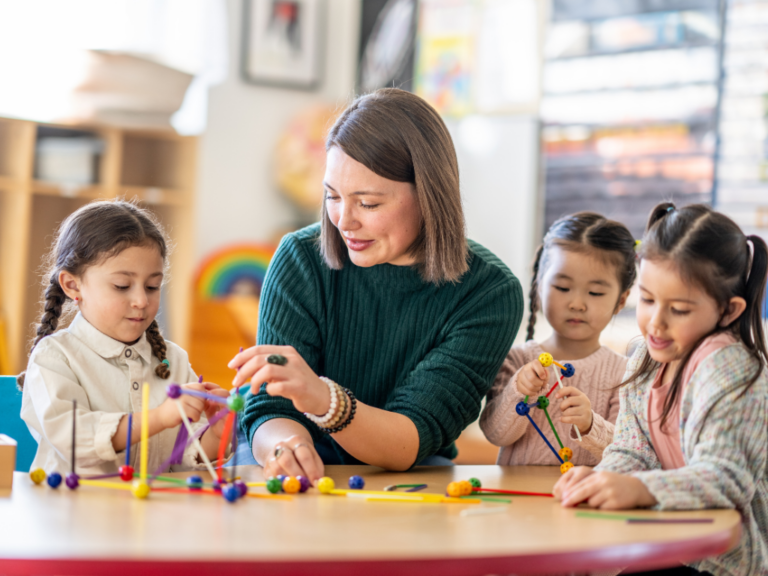 Nauczycielka prowadząca zajęcia edukacyjne z dziećmi przy stoliku